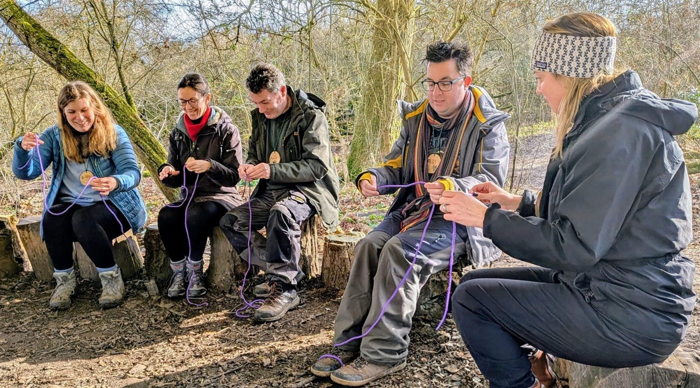 Trainees gathered around a small fire setup learning practical fire skills